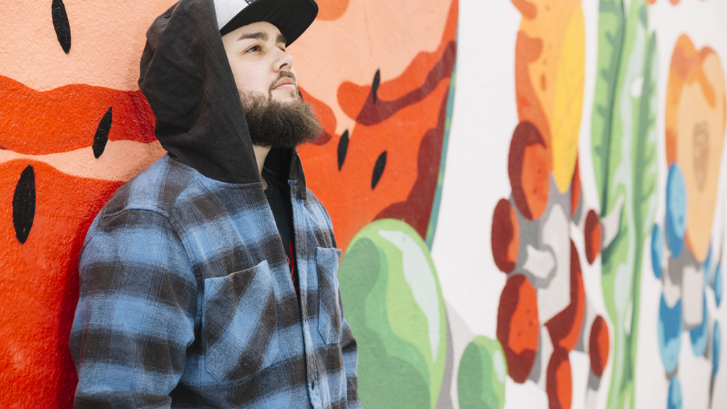 beard man standing front colorful graffiti wall